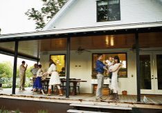 Multigenerational family standing on porch of home after dinner at twilight